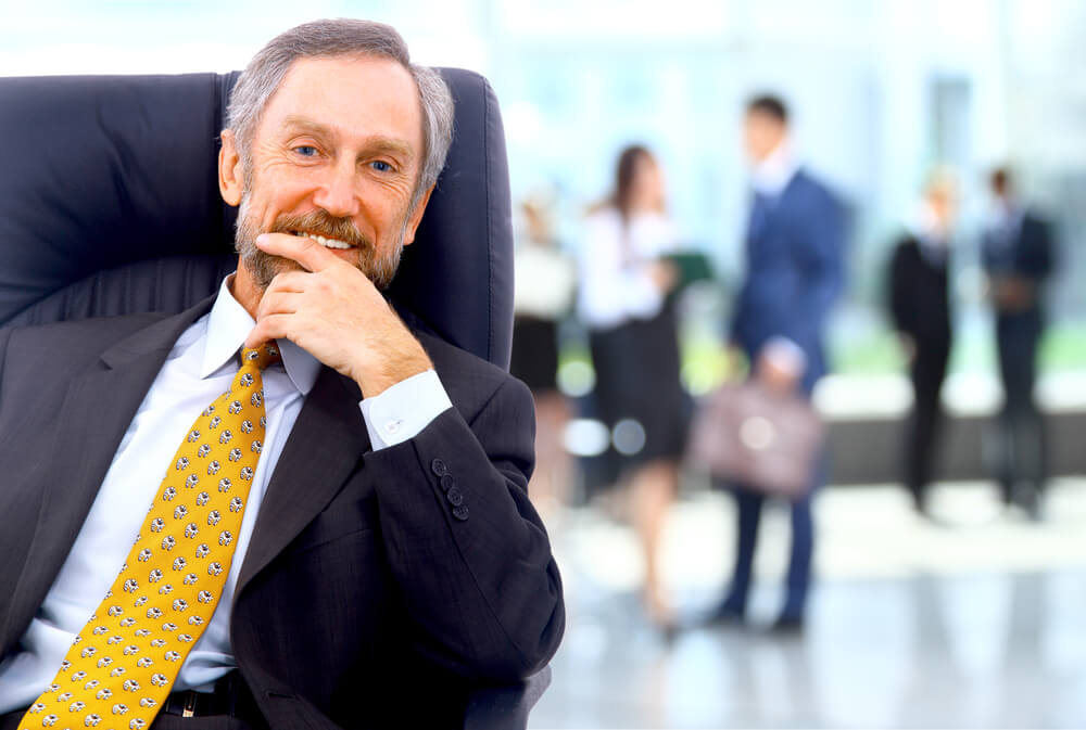 modelos de gestão, homem de terno e gravata sorrindo com a mão no rosto