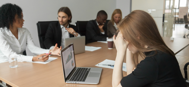 disciplina no trabalho ambiente corporativo onde uma reunião está em andamento. Algumas pessoas estão interagindo de forma ativa, enquanto outra parece preocupada ou sobrecarregada, com as mãos na cabeça