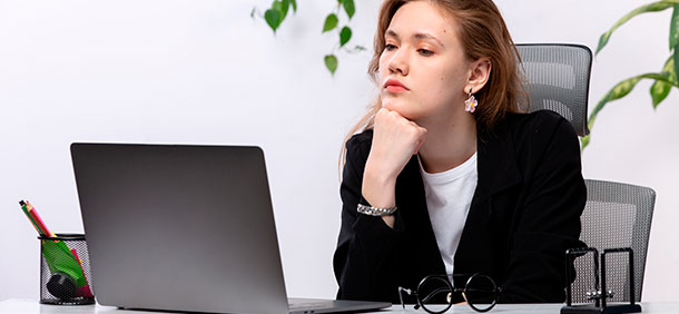 mulher com as maos no queixo olhando para o notebook com semblante de dúvid