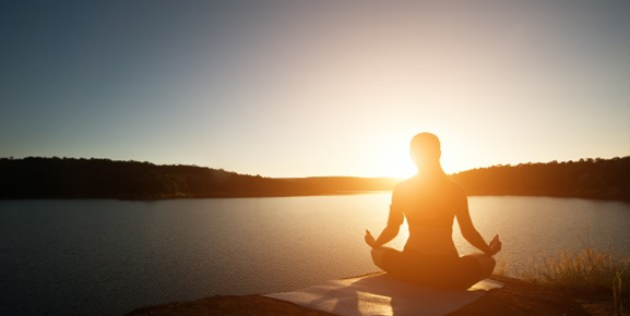 saúde física e mental, mulher meditando em frente ao por do sol