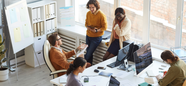 ambiente de escritório moderno e colaborativo, com uma equipe reunida e interagindo de forma descontraída e produtiva