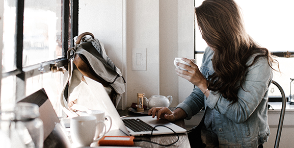 liderança de equipe, mulher trabalhando em notebook segurando um café