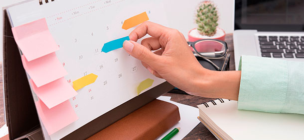 como organizar uma agenda pessoal e profissional, mão organizando um calendário com marcadores coloridos