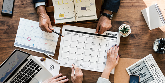 mãos femininas e masculina em cima de calendário fazendo sua organização em equipe