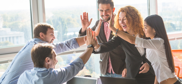 equipe motivada no trabalho comemorando juntos com hight five em um ambiente de escritorio iluminado