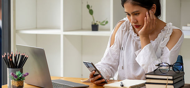 mulher olhando o celular enquanto trabalha, improdutiva