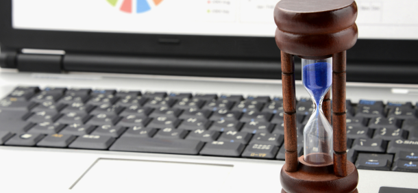 ampulheta sobre um notebook, simbolizando a importância da gestão do tempo no ambiente de trabalho