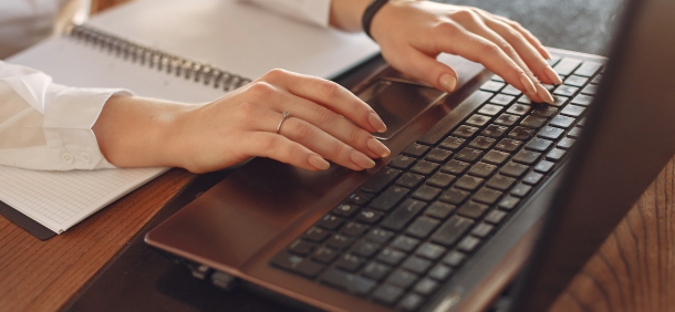 produtividade pessoal profissional digitando em laptop e planejando tarefas em caderno ao lado