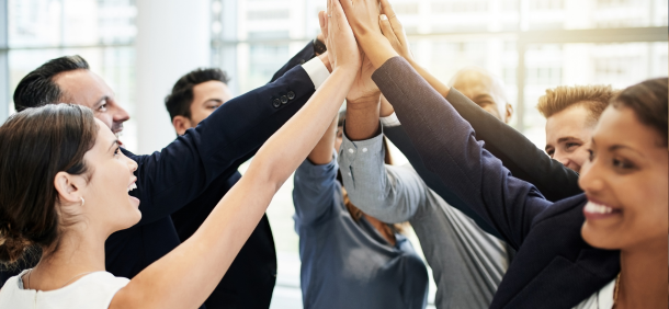 Equipe celebrando resultado com as mãos unidas, representando colaboração e alto desempenho em equipe